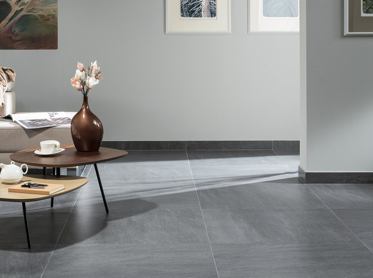 RAKO | Velkoformátová dlažba v tmavě šedé barvě ze série Quarzit využitá v obývacím pokoji.